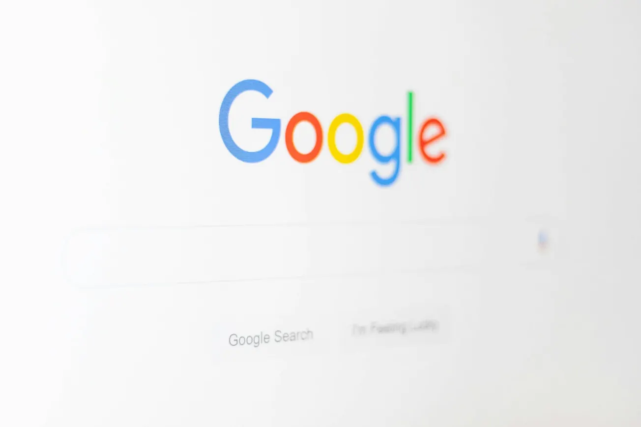The image shows a close-up of the Google homepage on a computer screen. The Google logo is prominently displayed above the search bar.