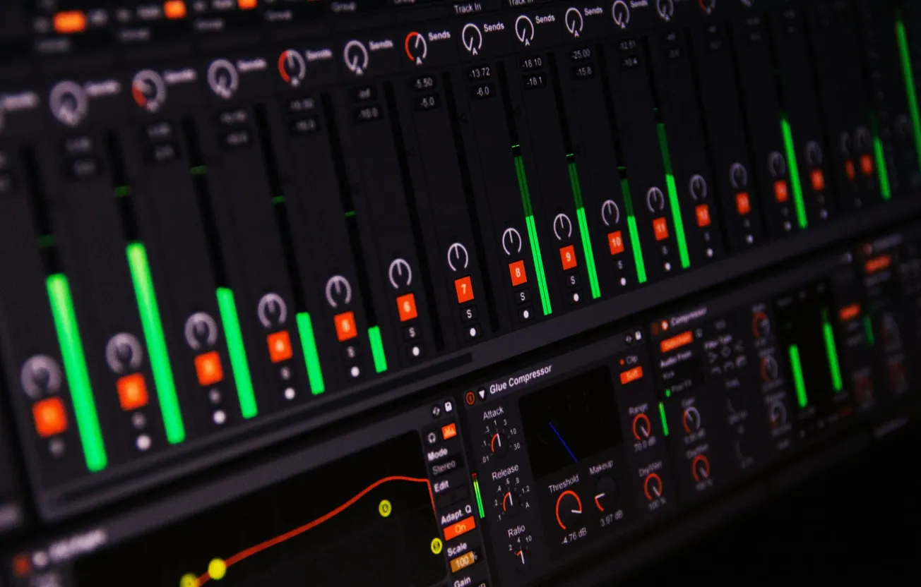 Close-up of a digital audio mixer interface with glowing green and red level meters, dials, and controls, creating a high-tech, focused atmosphere.