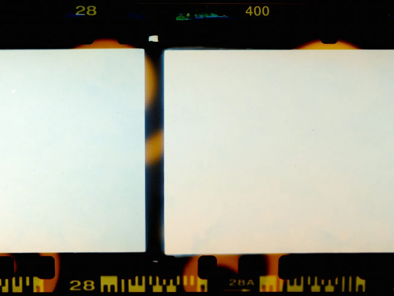Close-up of two blank film strips with dark edges and orange light leaks. Numbers "28" and "400" visible, evoking a nostalgic, retro feel.