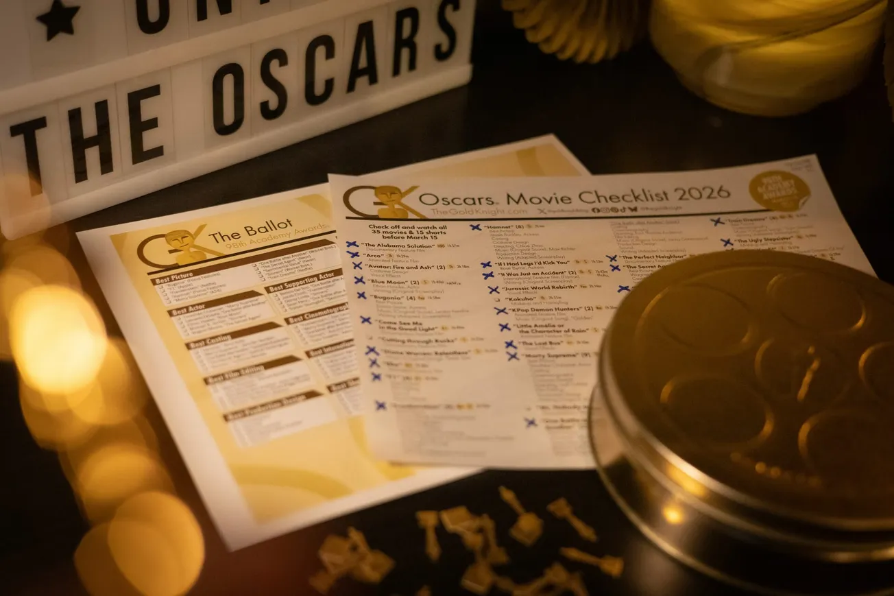 Illuminated Oscars-themed setup with a 2026 movie checklist and ballot papers on a table. A marquee reads "THE OSCARS," creating an elegant ambiance.
