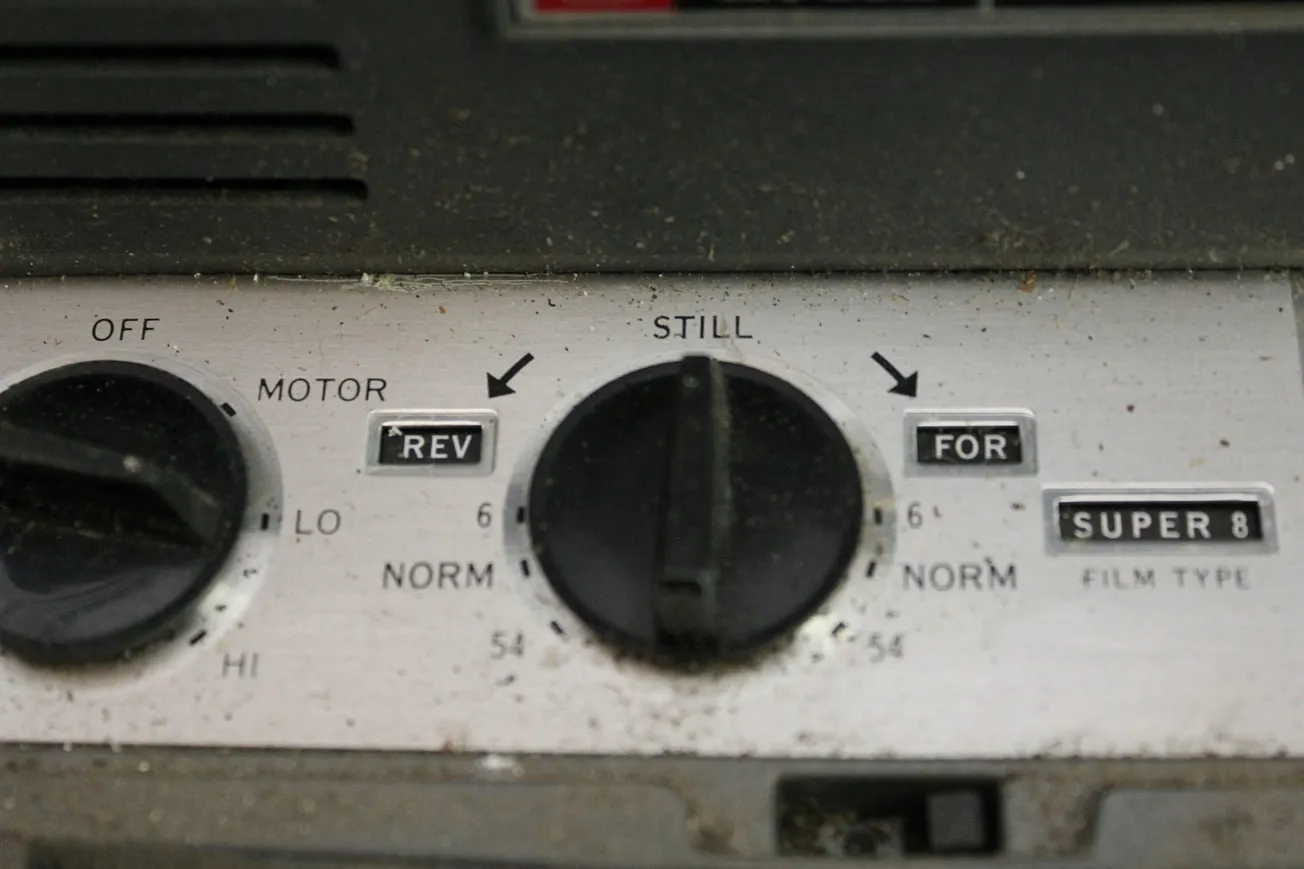 A close-up of the control panel of a dusty, vintage Super 8 film projector.