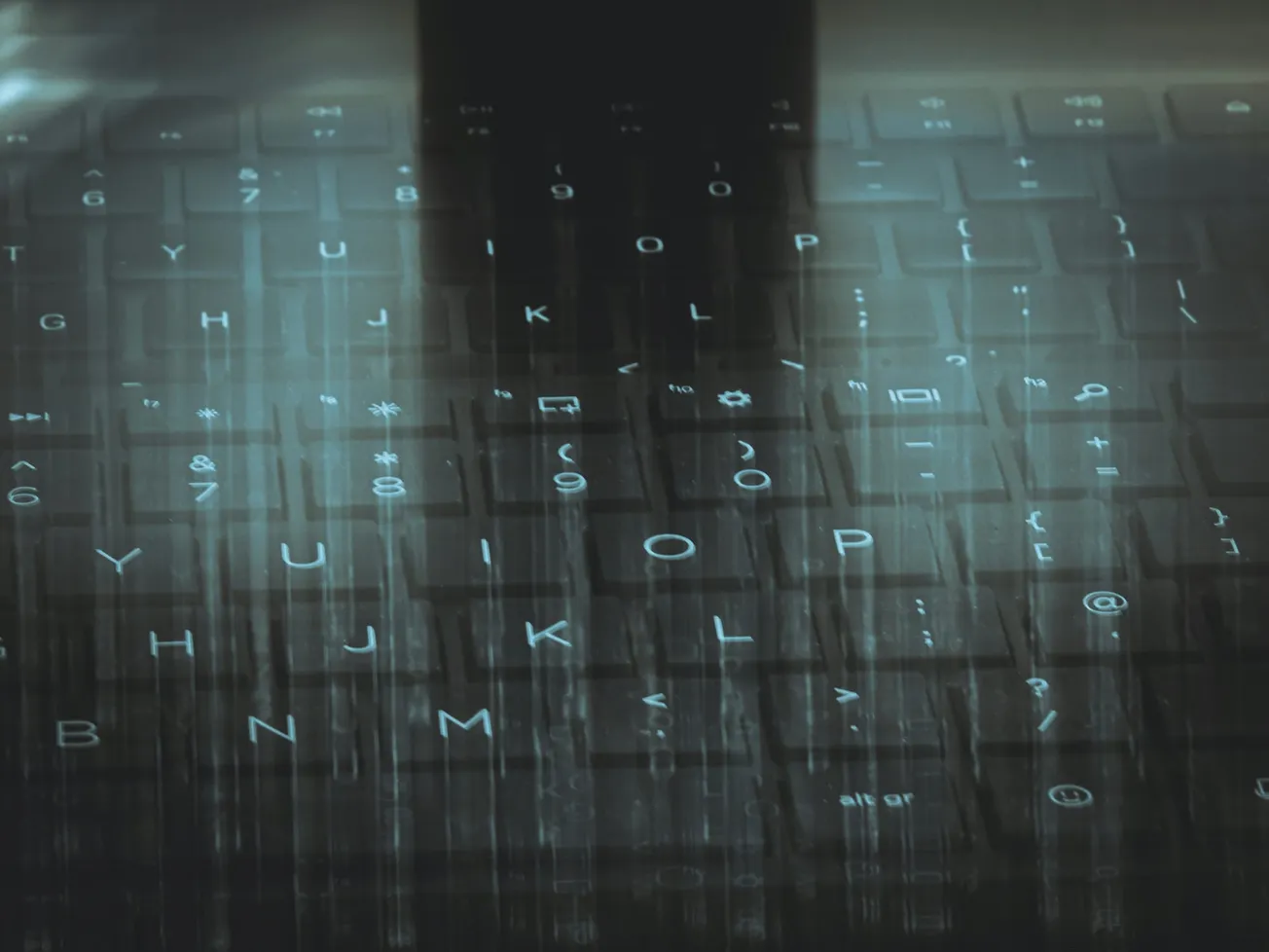 Blurred image of a computer keyboard with glowing keys, featuring letters and symbols. The overlay creates a digital, futuristic atmosphere.