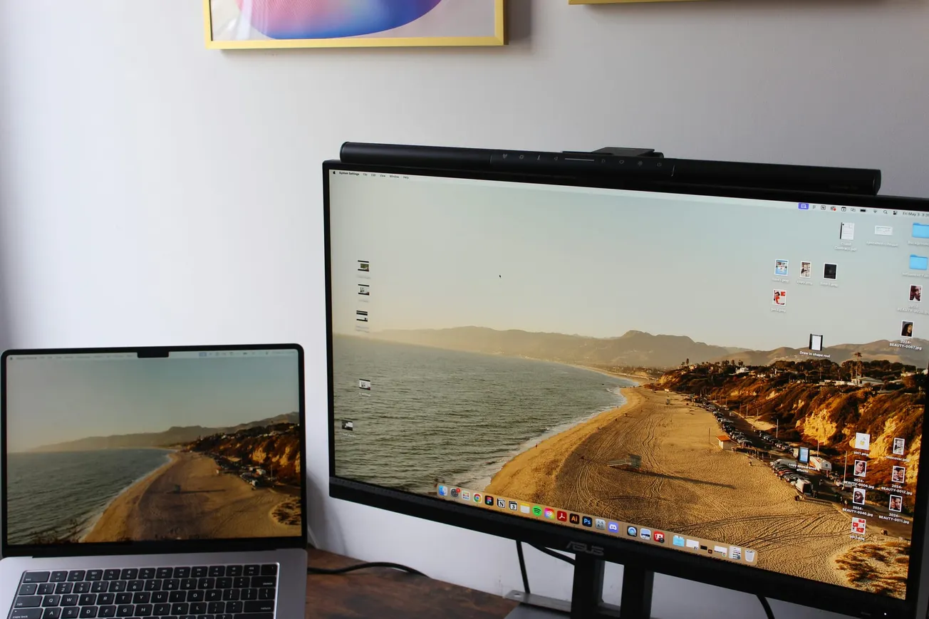 Dual monitors displaying a beach at sunset, set up on a wooden desk. Minimalist desktop icons, creating a tranquil and organized workspace.