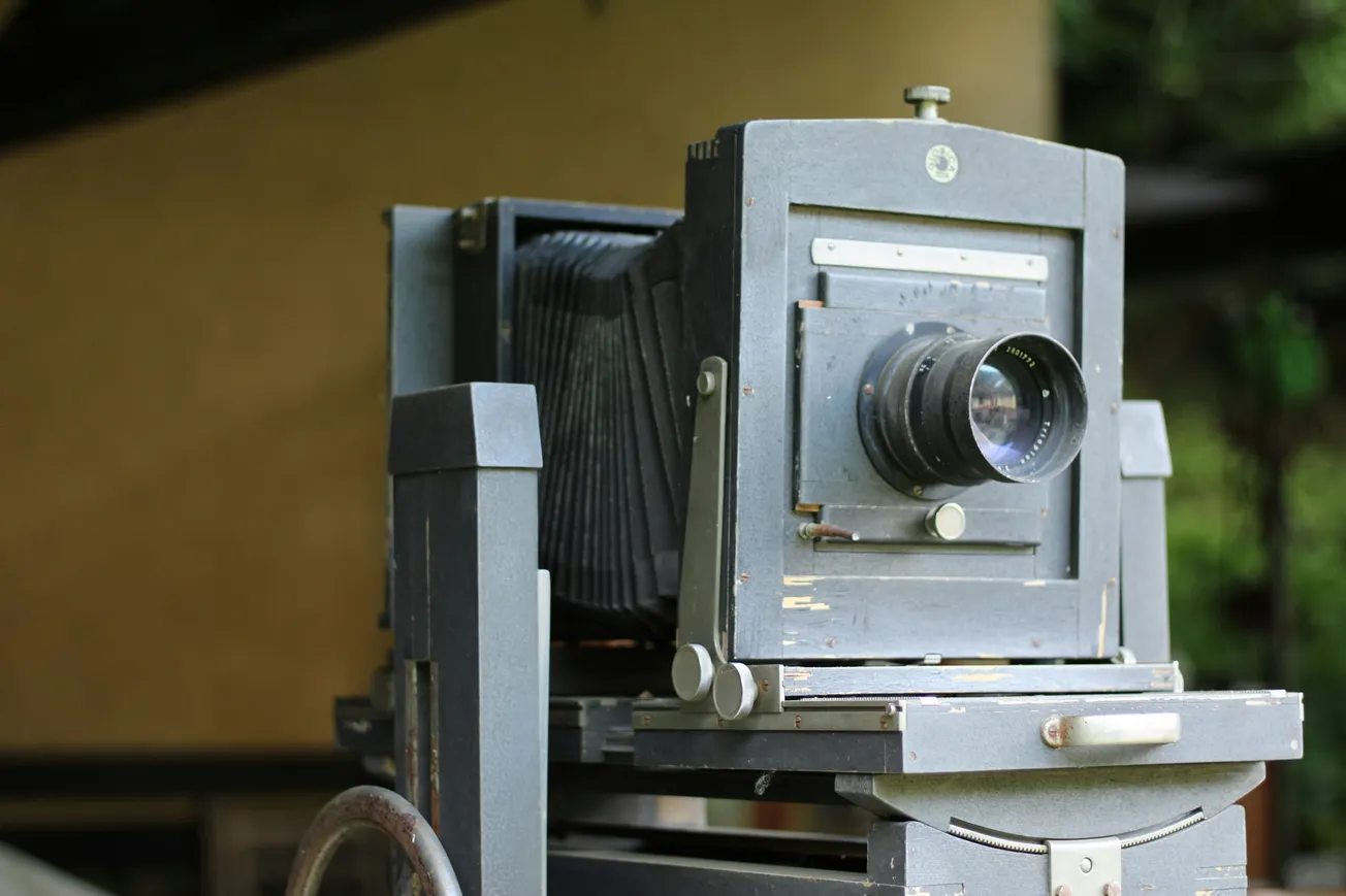 A vintage large format camera with a wooden body and bellows is on display. The scene evokes a nostalgic and historical ambiance.