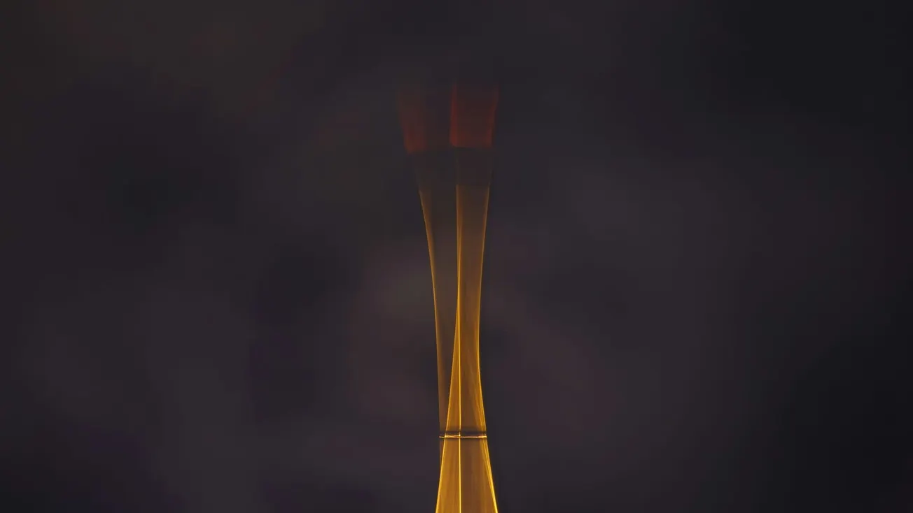 A gold tower with a slender silhouette glows softly in a dim, misty atmosphere, evoking a mysterious and elegant tone against a dark background.