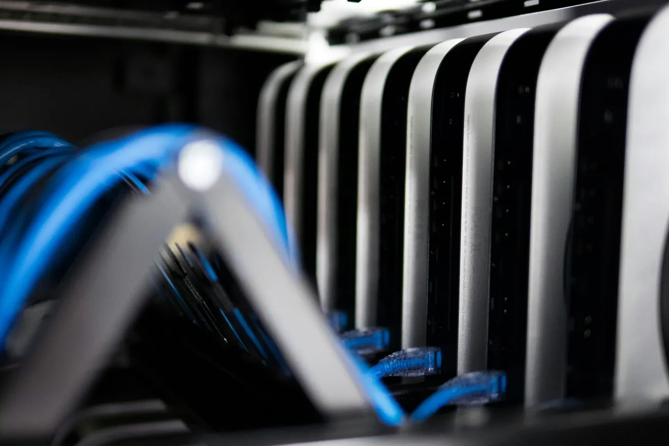 Close-up of a server rack with sleek metal casings and intertwined blue cables, conveying a modern and high-tech atmosphere.