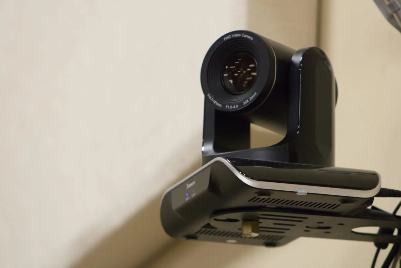 A black FHD video camera mounted on a wall bracket focuses forward. The lens is prominent, and the setup is sleek and modern, suggesting tech use.