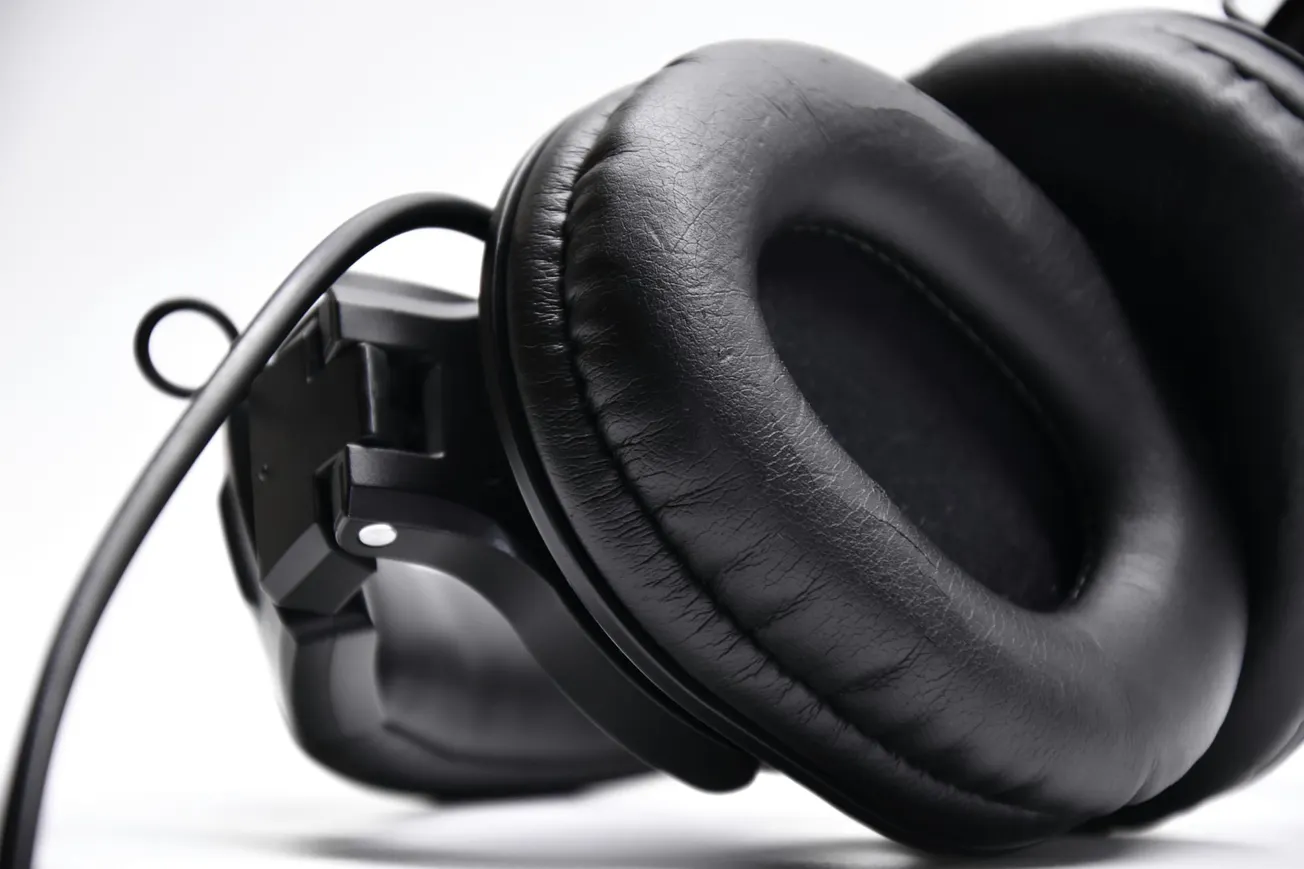 Close-up of a pair of black over-ear headphones against a white background. The image emphasizes the smooth, cushioned ear pads and sleek design.