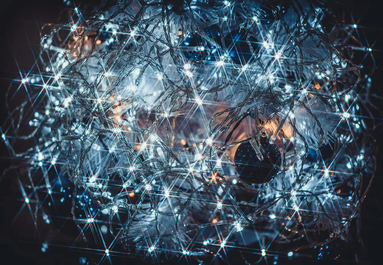 A cluster of bright white LED fairy lights intertwined with silver tinsel creates a sparkling and festive effect, evoking a sense of holiday cheer.