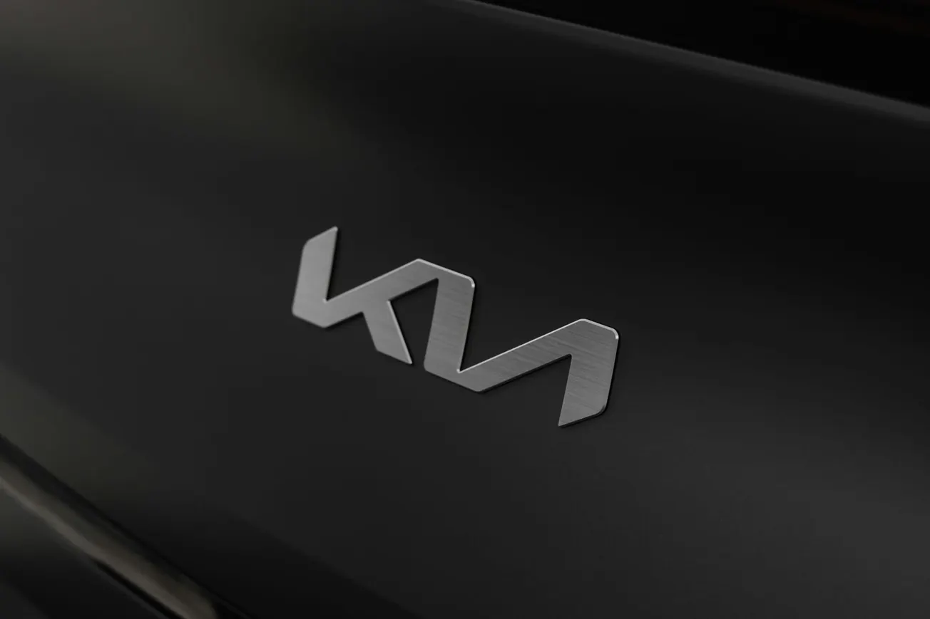 Silver "KIA" logo on a sleek, dark surface. The modern design and soft lighting convey a sense of elegance and innovation in automotive branding.