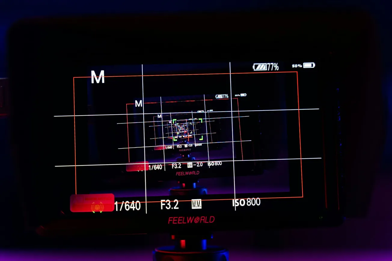 Close-up of a digital camera screen displaying infinite screen-within-a-screen effect. Visible settings include ISO, aperture, and battery life.