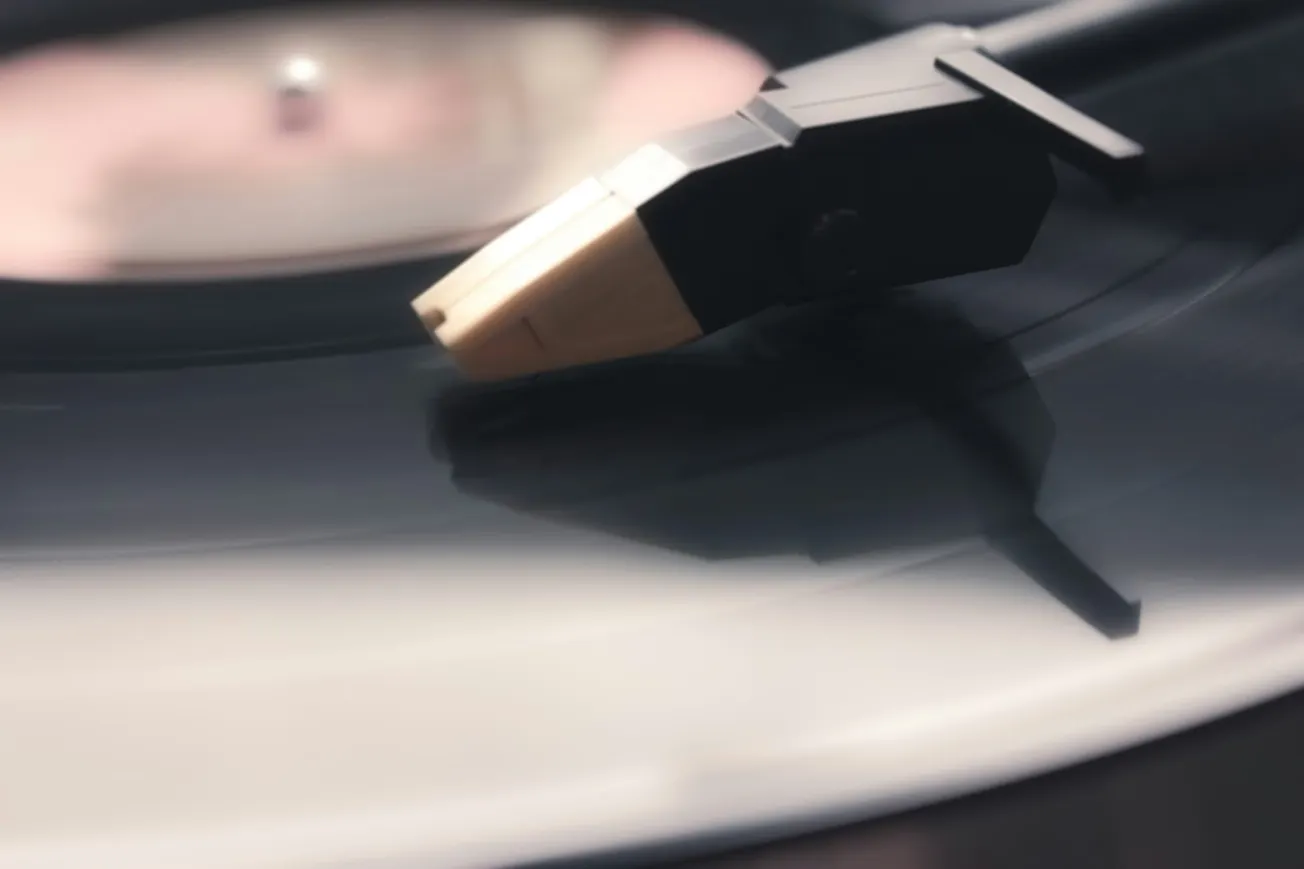 Close-up of a vinyl record player needle on a spinning black record. The scene conveys a vintage, nostalgic mood with soft lighting and gentle focus.