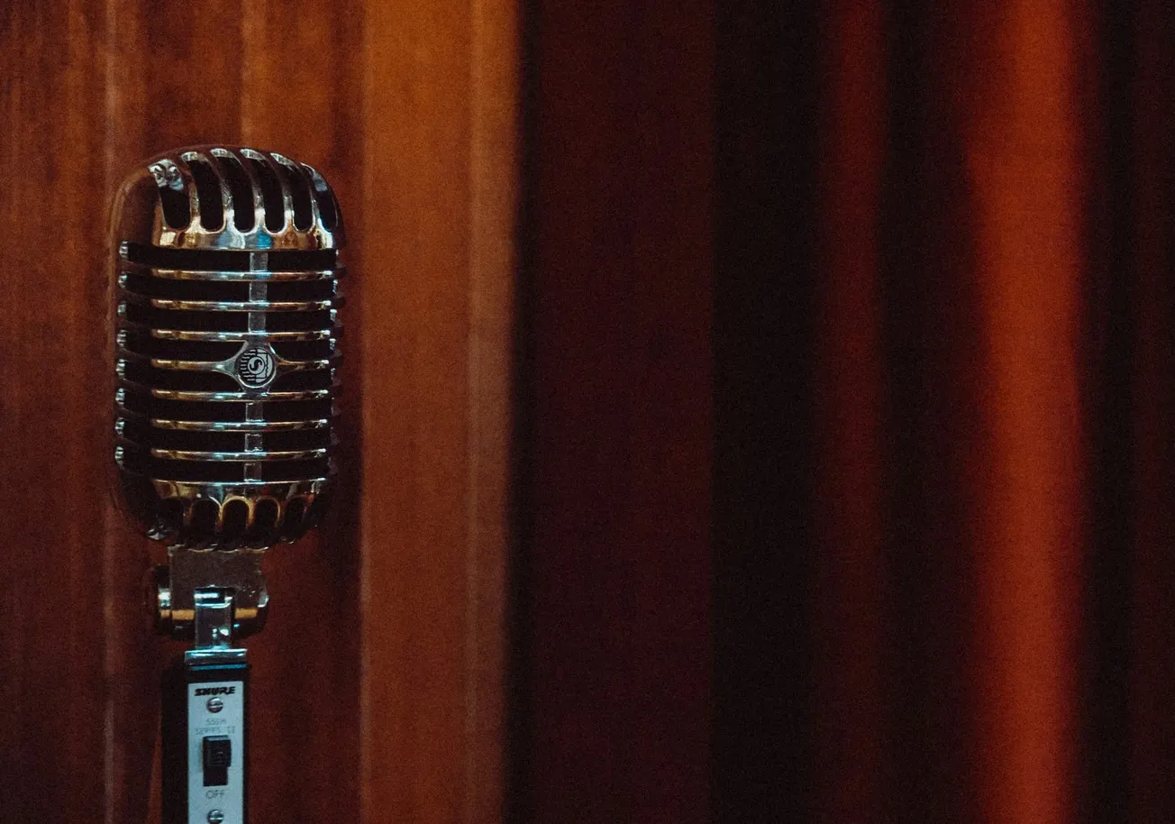 Vintage microphone on stand against rich wooden background. The warm tones evoke a nostalgic, classic atmosphere, ideal for a retro-themed setting.