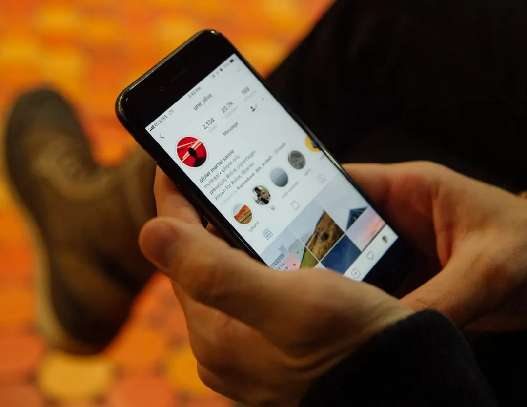 A person views a mobile phone displaying a social media feed.
