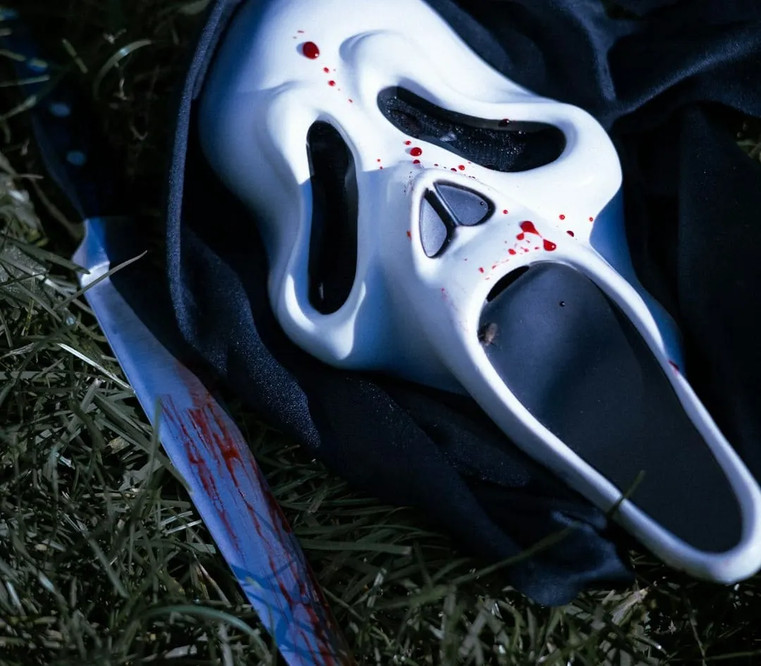 A dramatic close-up of a masked figure, reminiscent of Ghostface, with a blurred background suggesting classic film reels and a moody, suspenseful atmosphere.