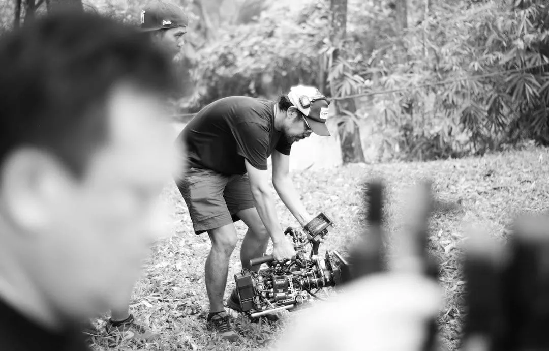 A director observes a scene being filmed outdoors, showcasing a crew meticulously arranging practical set elements under natural lighting.