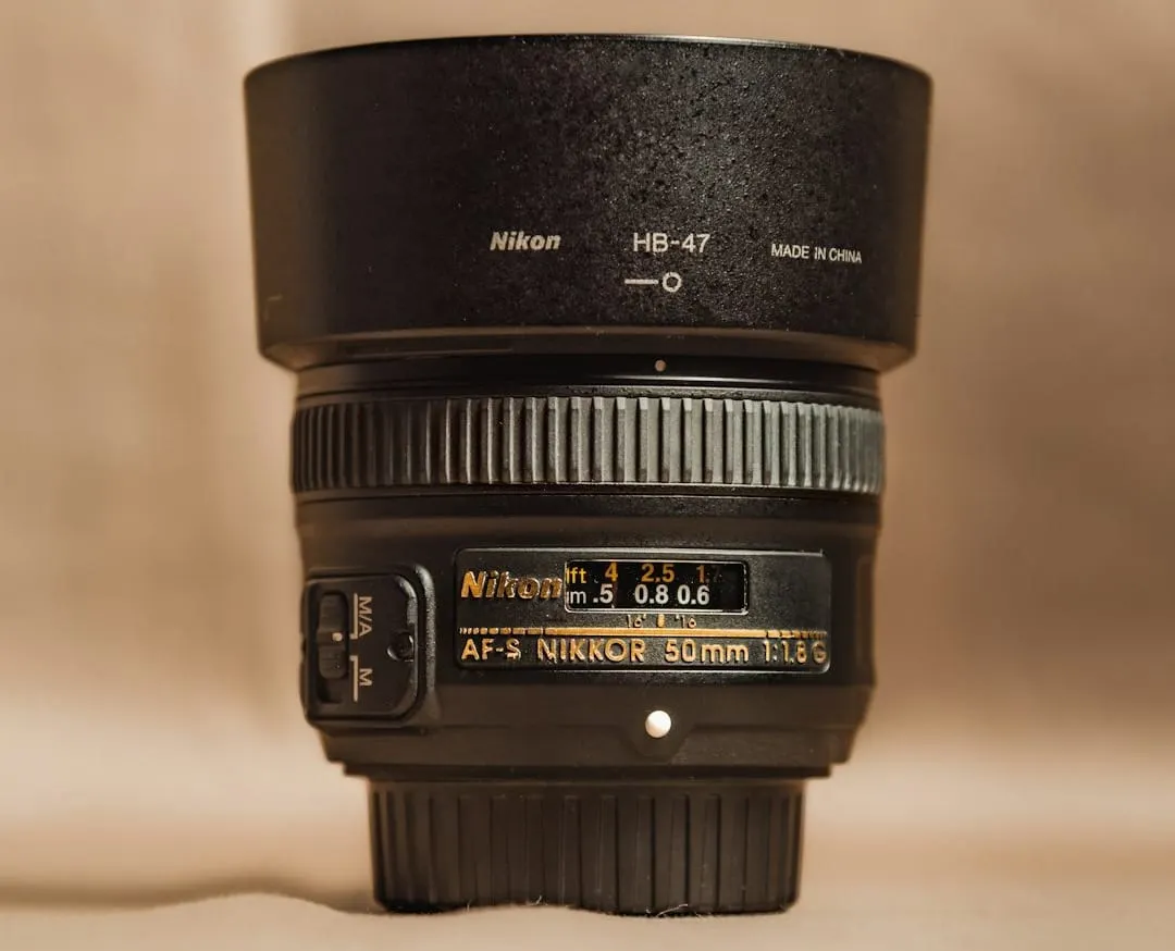 A black Nikon FTZ II lens adapter seamlessly connects an older F-mount DSLR lens to a modern Z-mount mirrorless camera body, illustrating equipment versatility.
