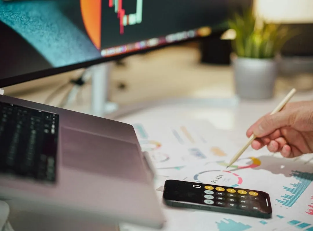 A focused individual analyzes digital marketing performance data on a laptop screen, optimizing ad budgets for content promotion.