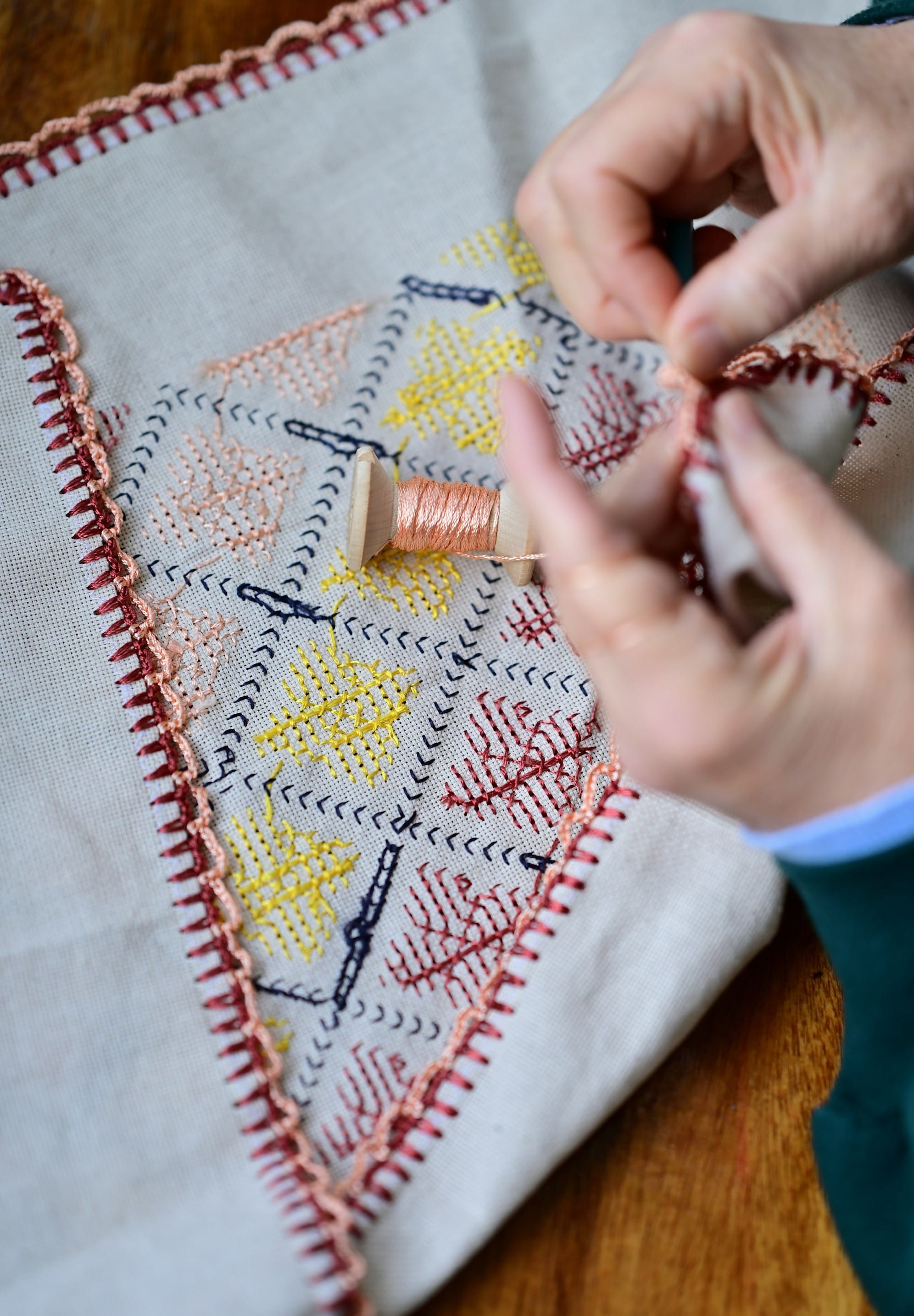 a woman is working on a cross stitch project