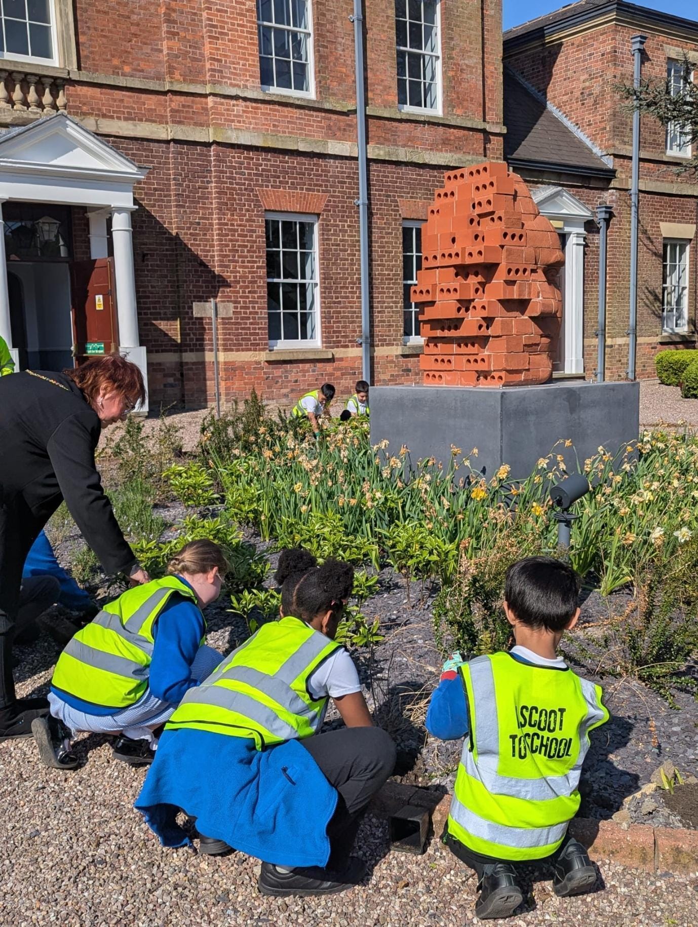 Pupils from Etruscan Primary School plant heather at base of Capo sculpture