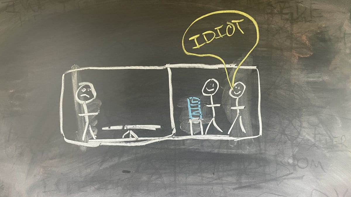 Chalk on black. A leadership table of stick figures facing a larger figure at the head, frozen mid-gesture, the others' speech marks crossed out. One red line on the frozen figure.