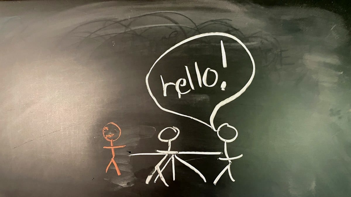 Chalkboard drawing of an empty chair at the head of a table with a faint figure behind glass, chalk text reading present but not here.