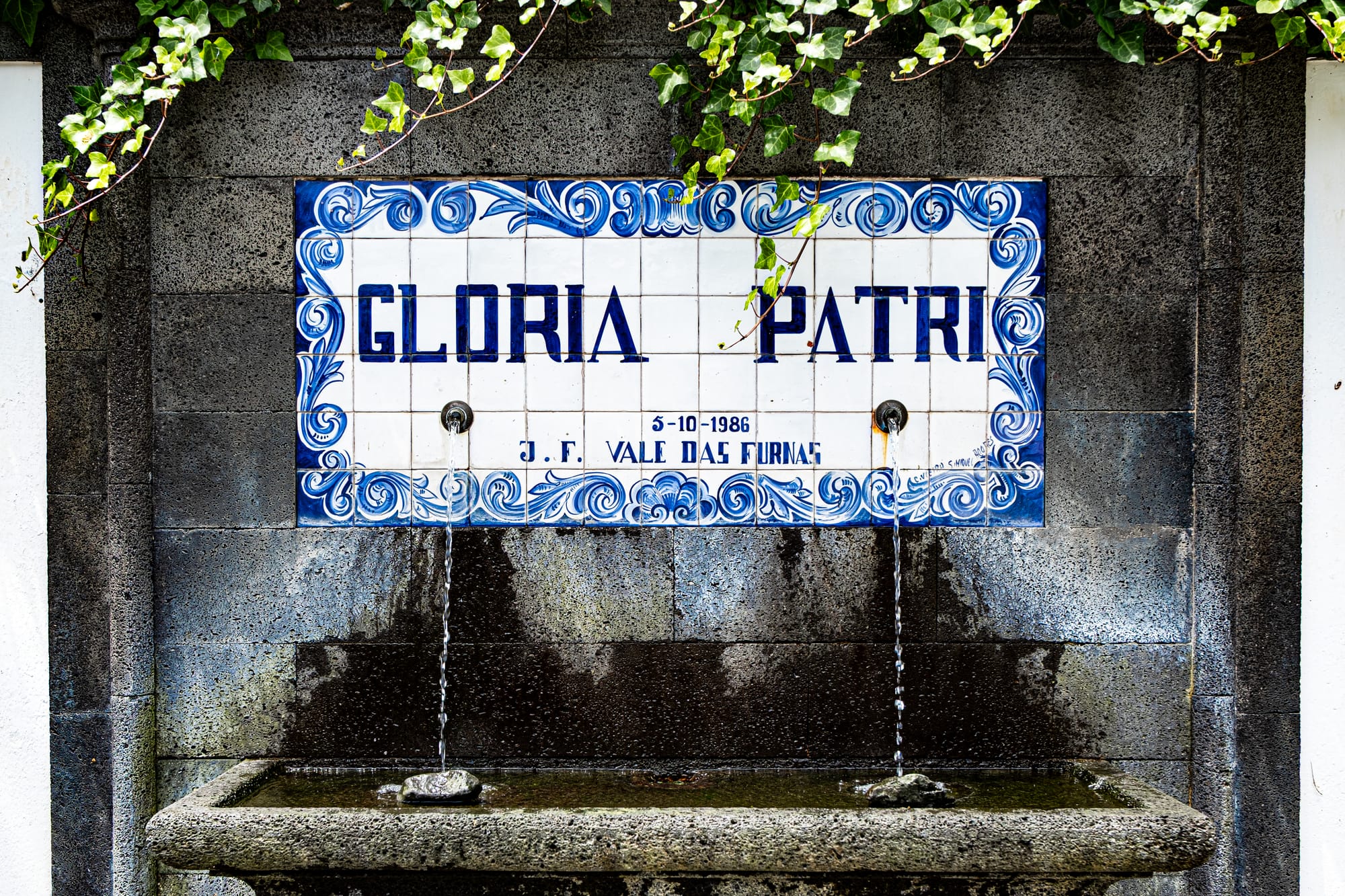 Tiled Glória Patri spring water fountain with ivy above and water flowing from three spouts
