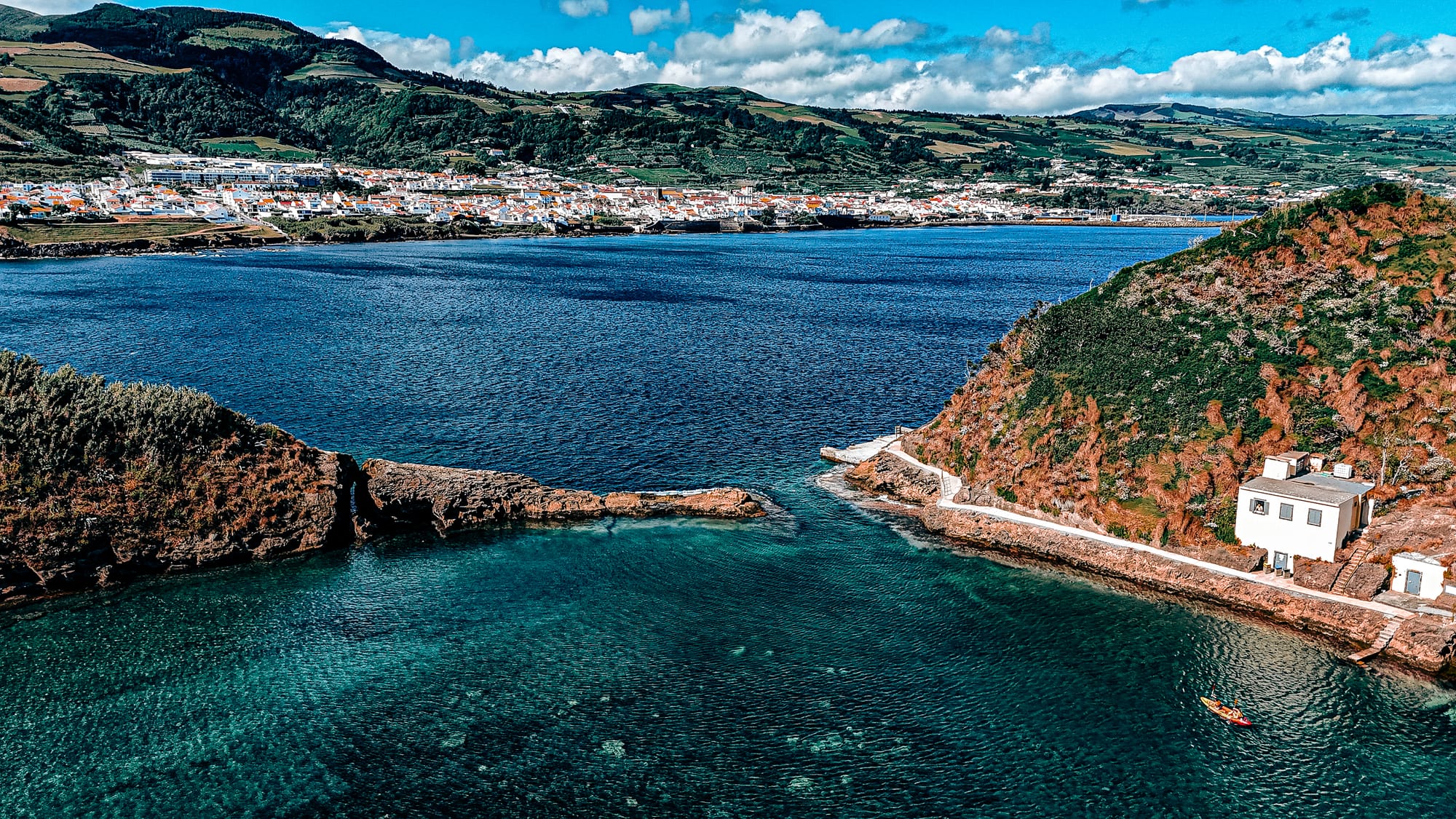 Aerial view of Ilhéu de Vila Franca do Campo showing the Boquete channel, with a kayak in the foreground and the town of Vila Franca in the background across the water
