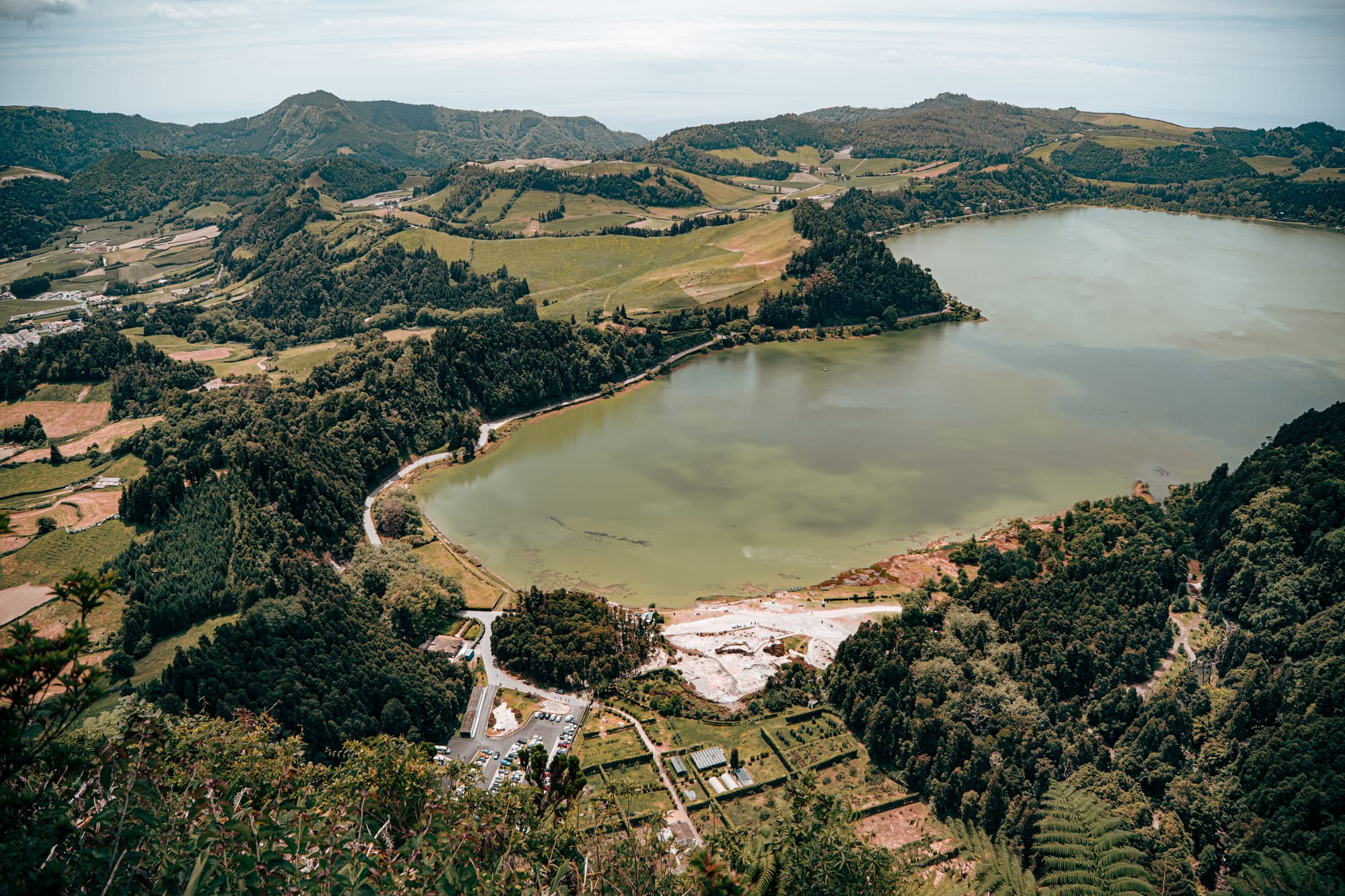Panoramic view of Lagoa das Furnas surrounded by forests, hills, and volcanic terrain