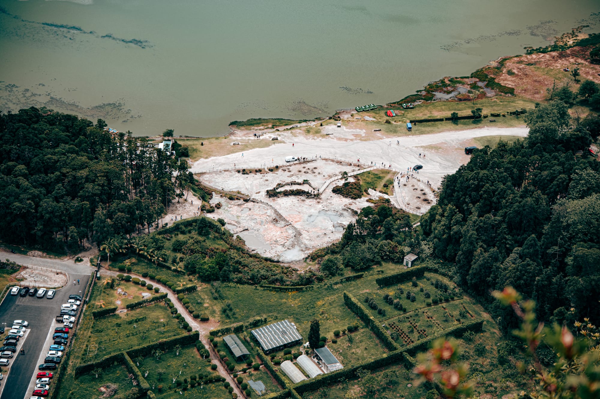 Aerial view of Furnas’ geothermal hot spring field beside a lake and manicured garden plots
