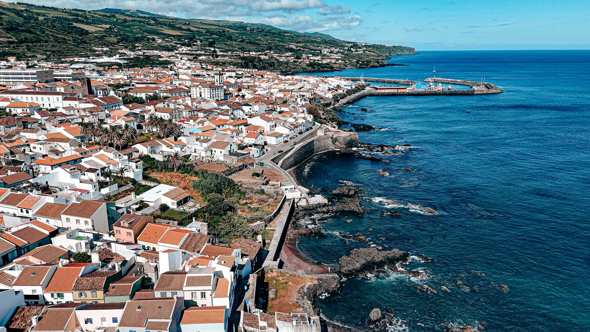 Aerial view of Vila Franca do Campo showing the waterfront, marina, and surrounding homes along the rocky Atlantic coast