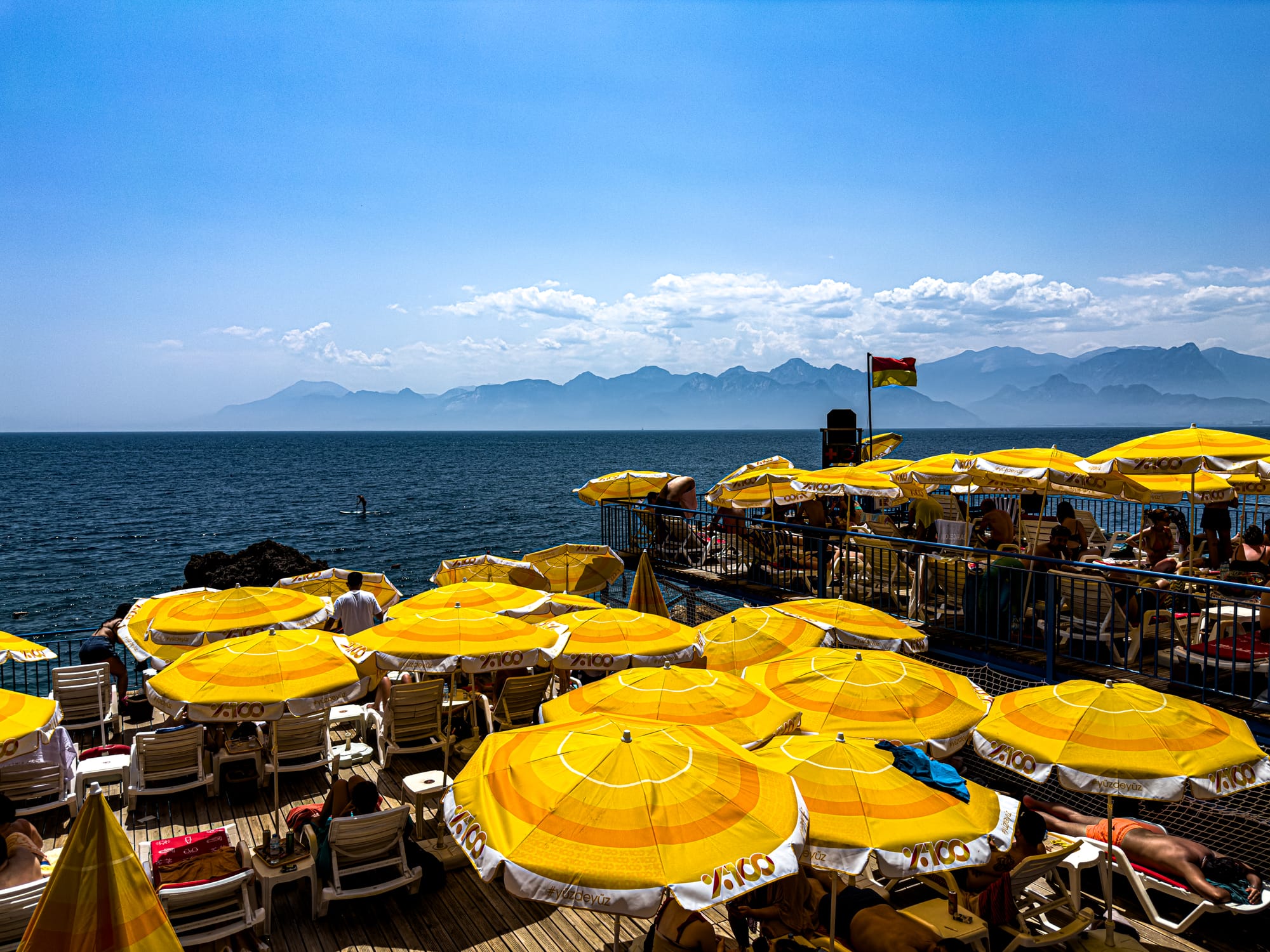 Rows of yellow umbrellas at İnciraltı Beach in Antalya with a panoramic view of the Mediterranean Sea and distant mountains