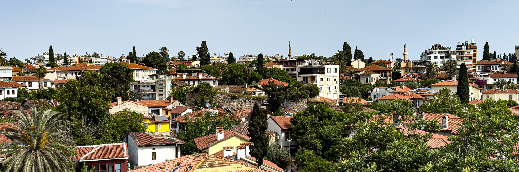 Panoramic view of Antalya’s Kaleiçi old town, with red tile roofs, minarets, and dense greenery
