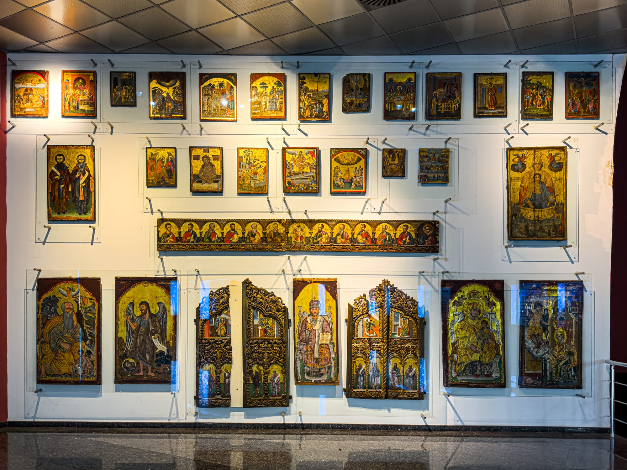 A display wall of religious icons and painted panels, many with gold backgrounds and depictions of saints and biblical scenes