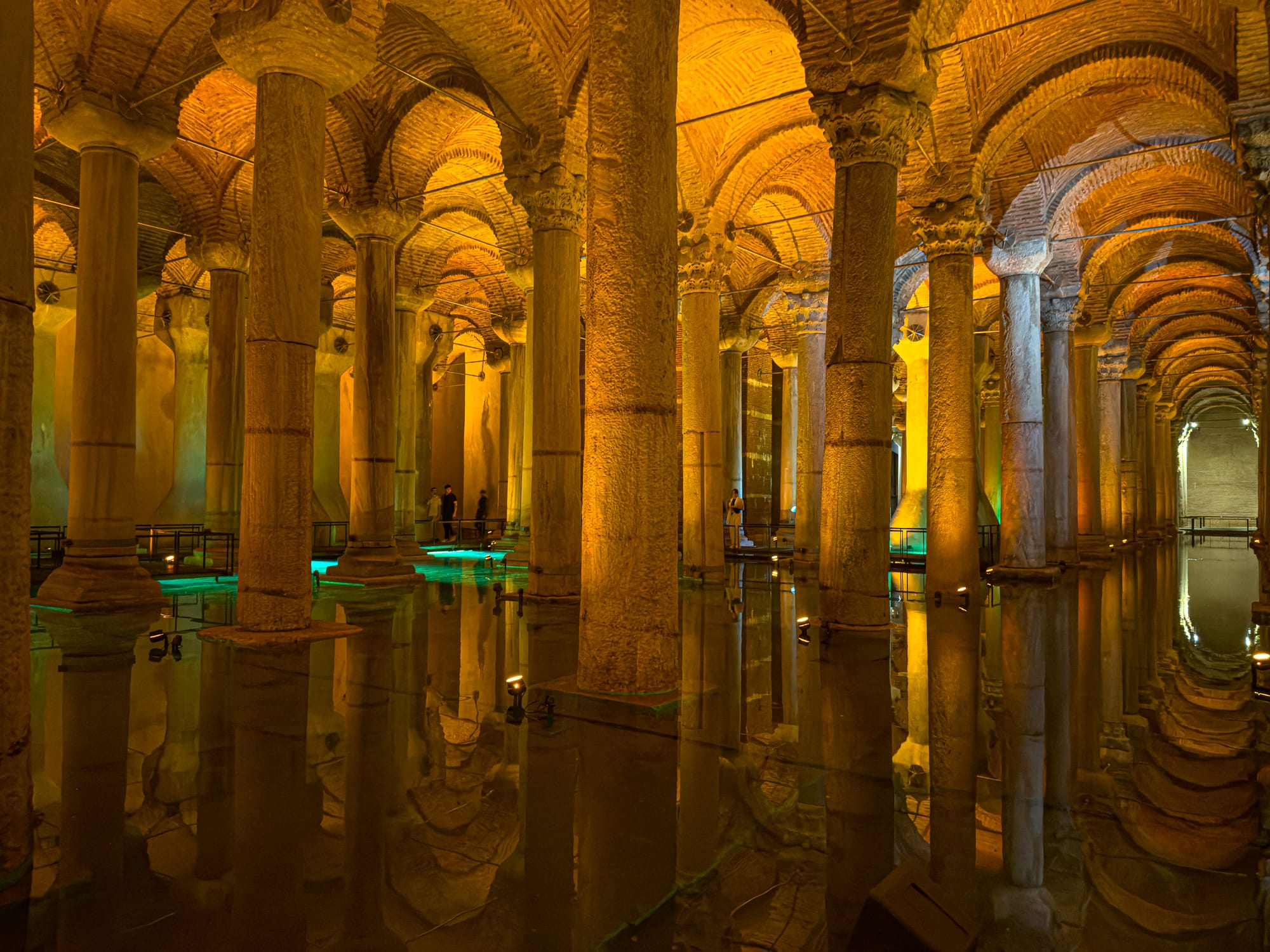 Wide view of the Basilica Cistern’s columns bathed in yellow-orange light with glowing water reflections