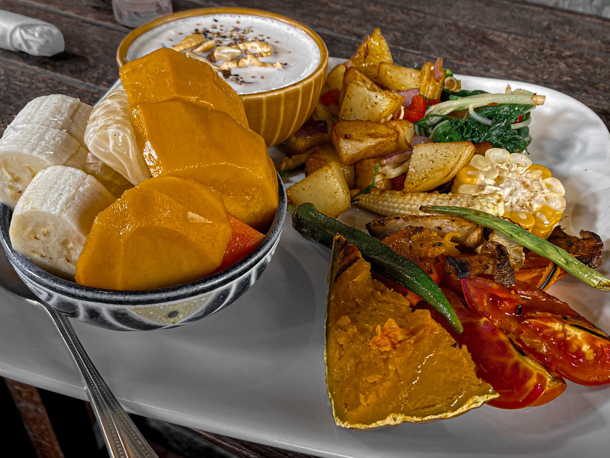 Bird’s Nest Café breakfast plate with fresh fruit, local porridge topped with nuts, sautéed potatoes, greens, corn, and grilled vegetables