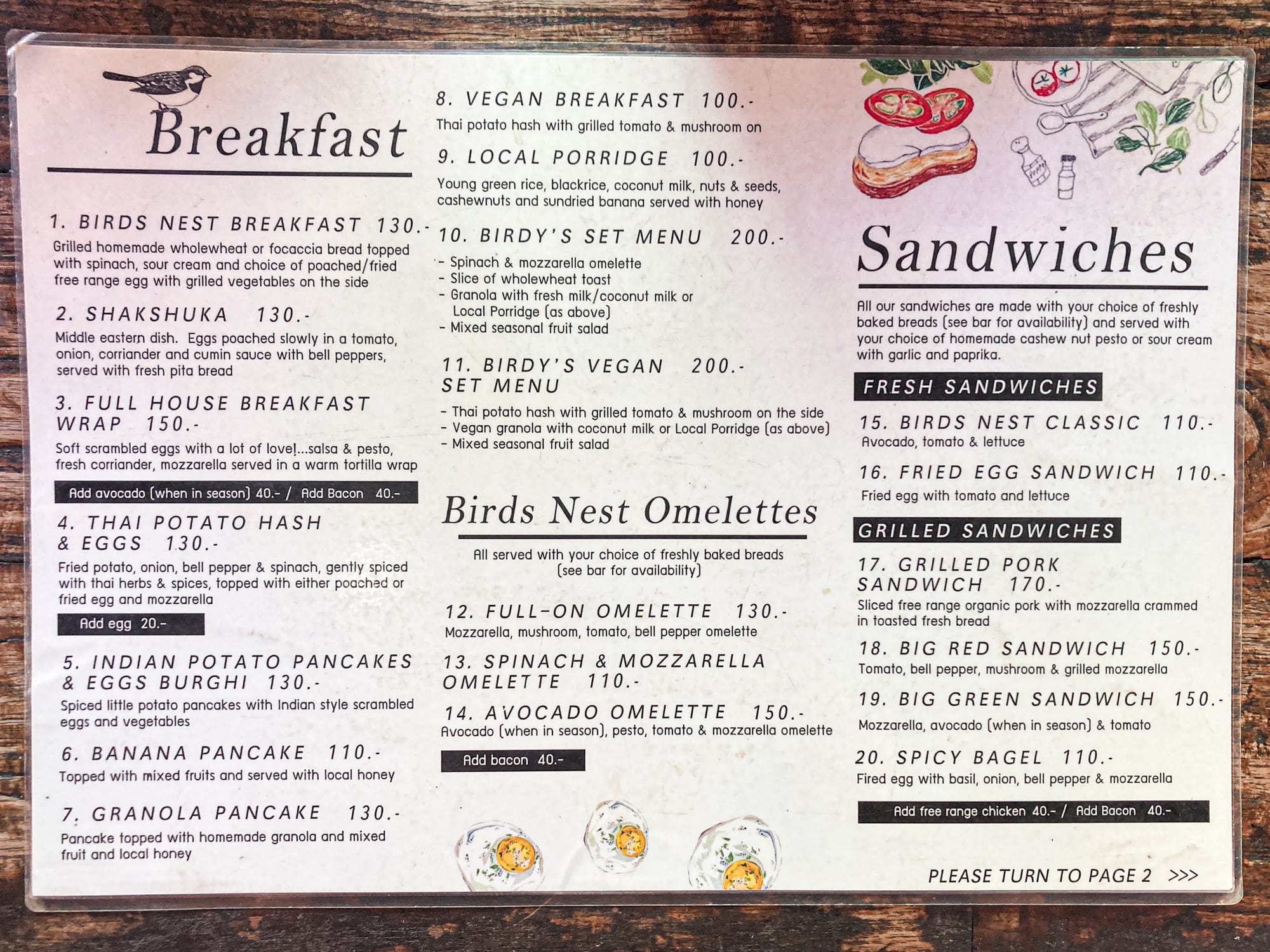 Bird’s Nest Café menu showing breakfast options such as shakshuka, pancakes, potato hash, vegan breakfast, local porridge, and omelettes, alongside sandwiches made with homemade bread including avocado, tomato, fried egg, and grilled vegetable varieties