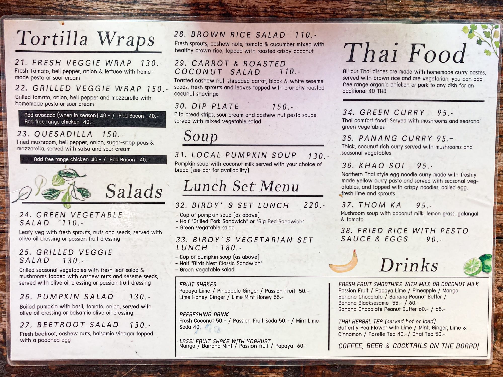 Bird’s Nest Café menu board showing a variety of dishes including tortilla wraps like the fresh veggie wrap and quesadilla, salads such as pumpkin and beetroot, Thai dishes including green curry, penang curry, khao soi, and fried rice with pesto, as well as local pumpkin soup, lunch set menus, fruit shakes, herbal teas, and smoothies