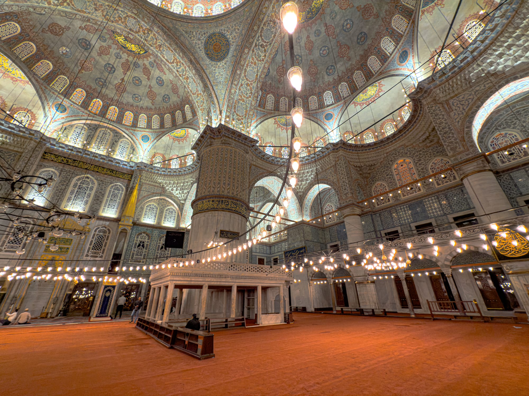 Golden chandeliers sweep across the prayer hall of the Blue Mosque beneath intricate tiled domes