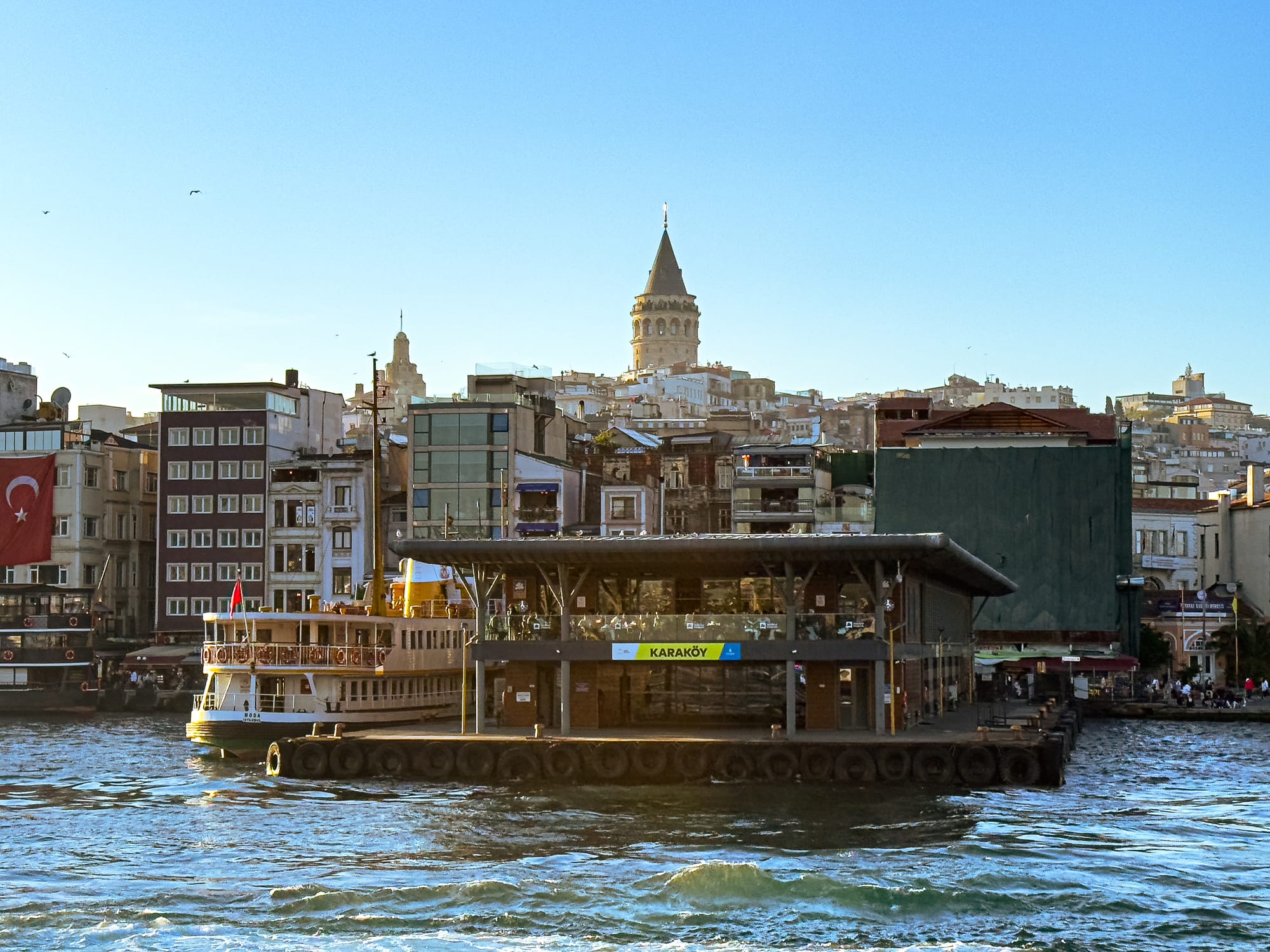 View of the Karaköy ferry terminal with the Galata Tower rising behind it at golden hour