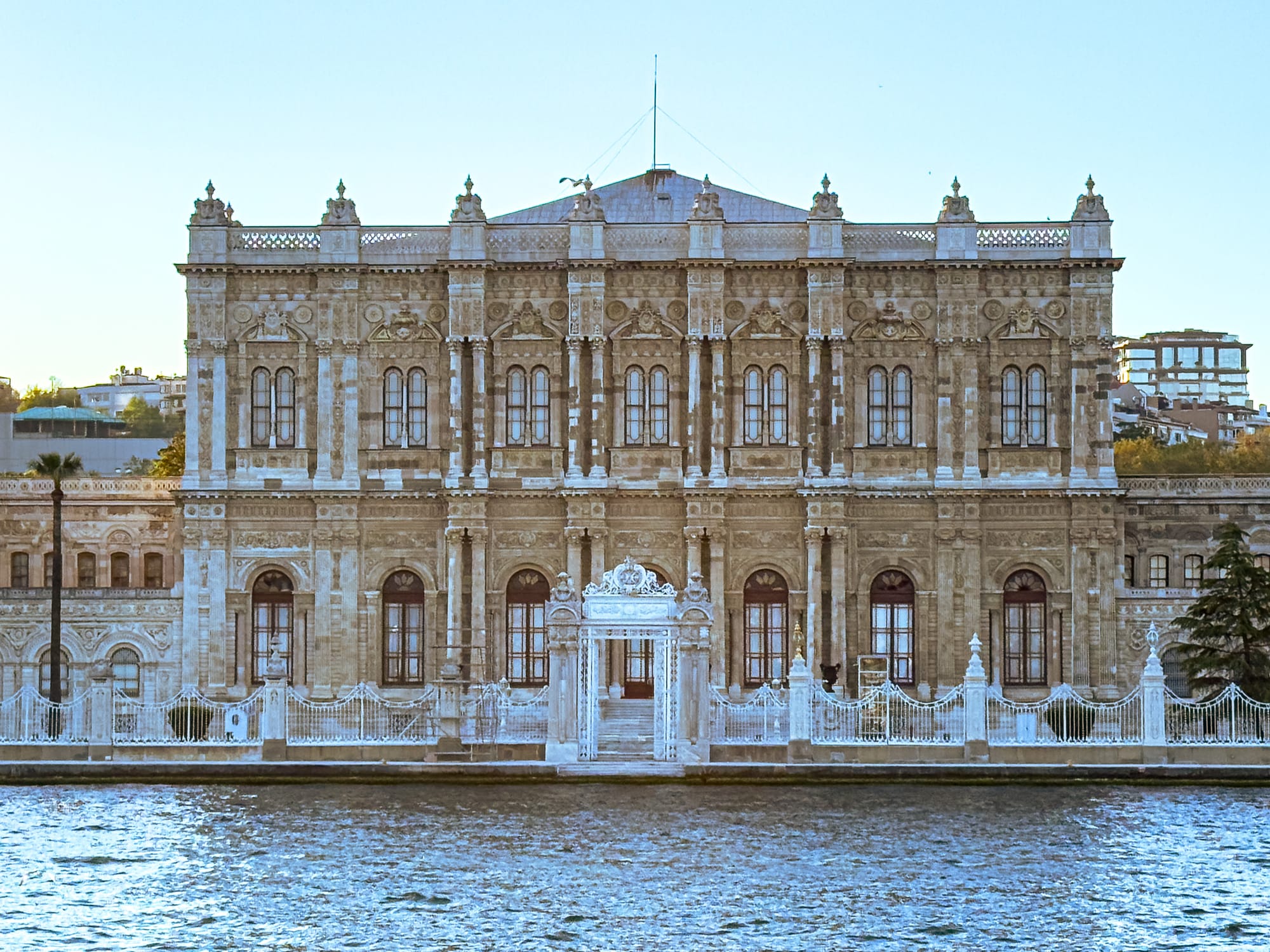 View of the ornate Dolmabahçe Palace façade from the Bosphorus during golden hour