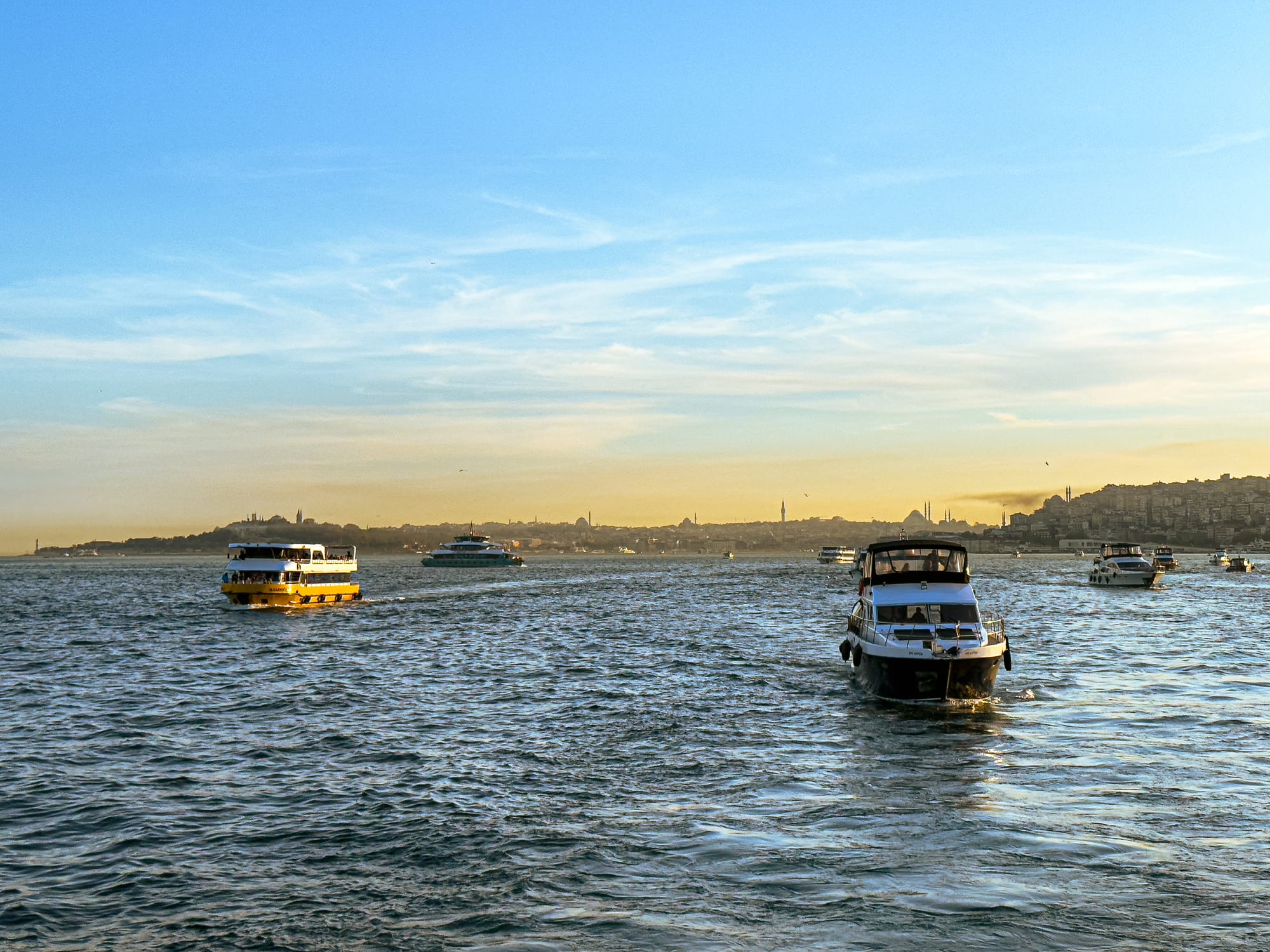 Boats glide along the Bosphorus during golden hour, with Istanbul’s skyline silhouetted in the distance