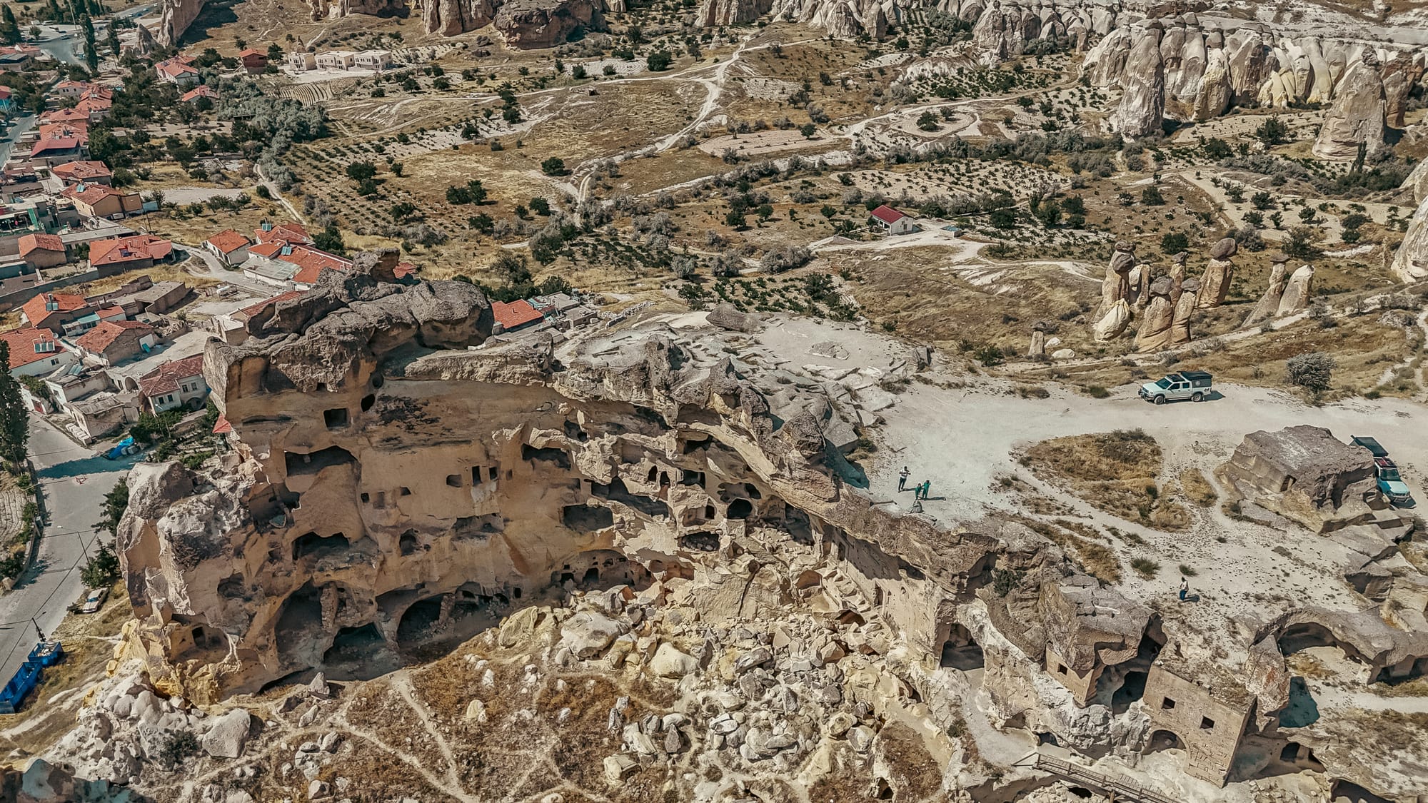 Aerial photograph of Çavuşin Castle in Cappadocia, showing ancient cave dwellings, surrounding valleys, and unique fairy chimney rock formations