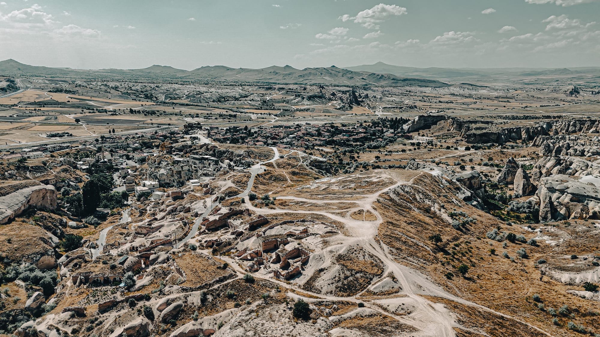 Aerial view of Çavuşin village in Cappadocia, showing rock formations, cave dwellings, and winding valley paths
