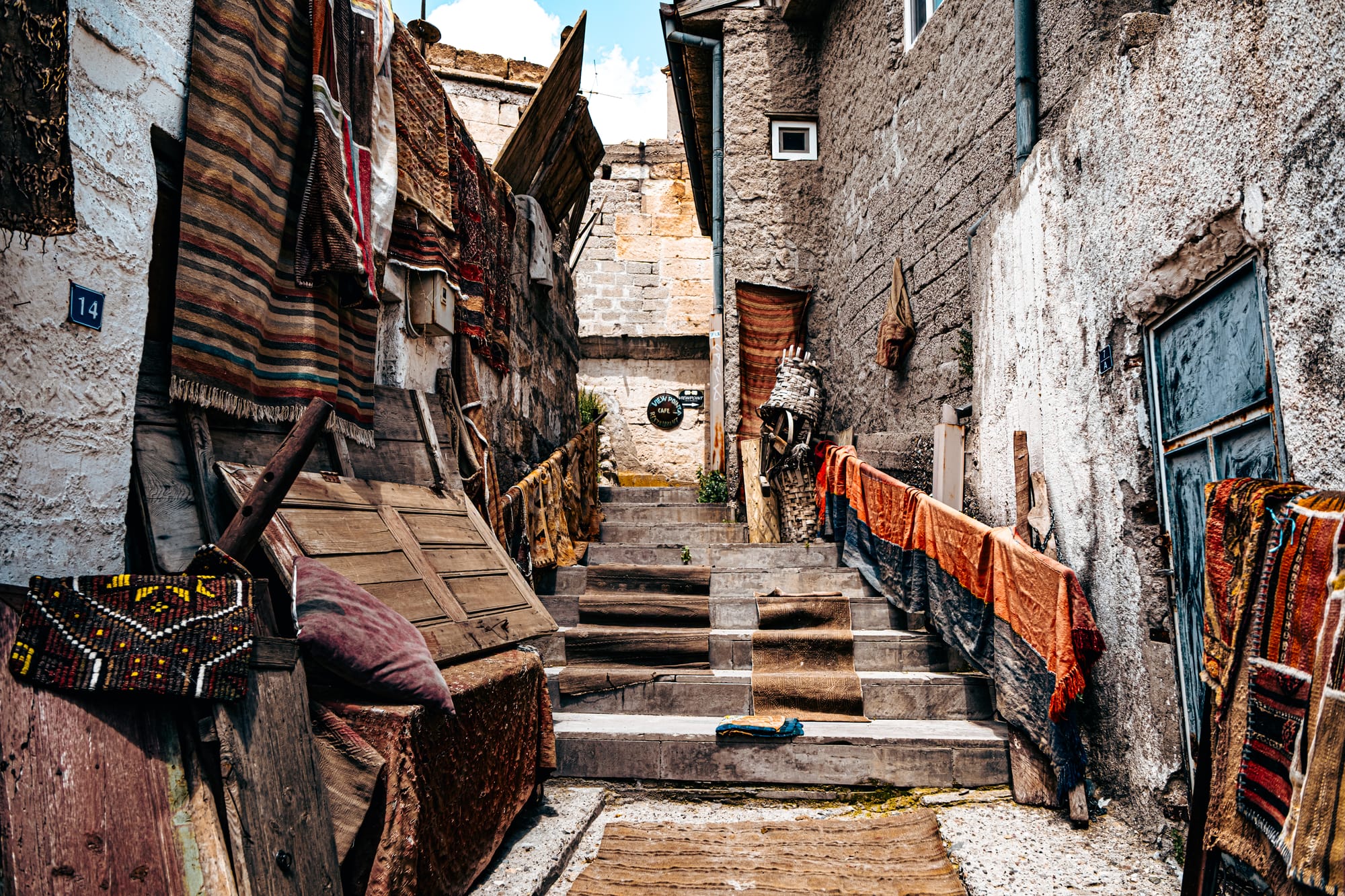 Stone stairway lined with colorful rugs and antique wooden doors at Cappadocia Cultural Antique Collection entrance in Göreme