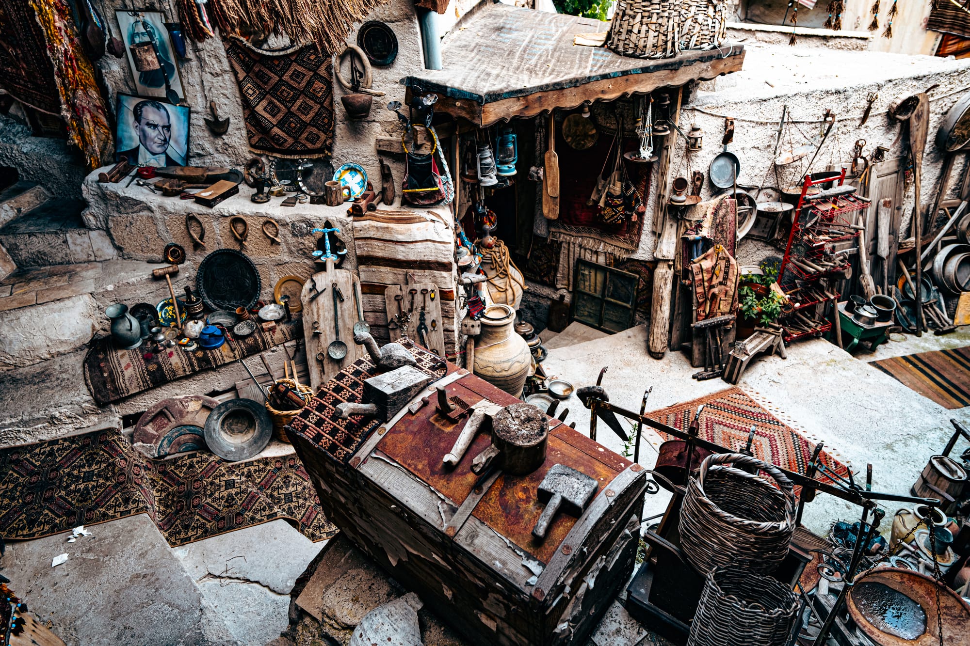Outdoor courtyard at Cappadocia Cultural Antique Collection filled with vintage artifacts, rugs, pottery, and traditional tools displayed on stone walls and wooden surfaces