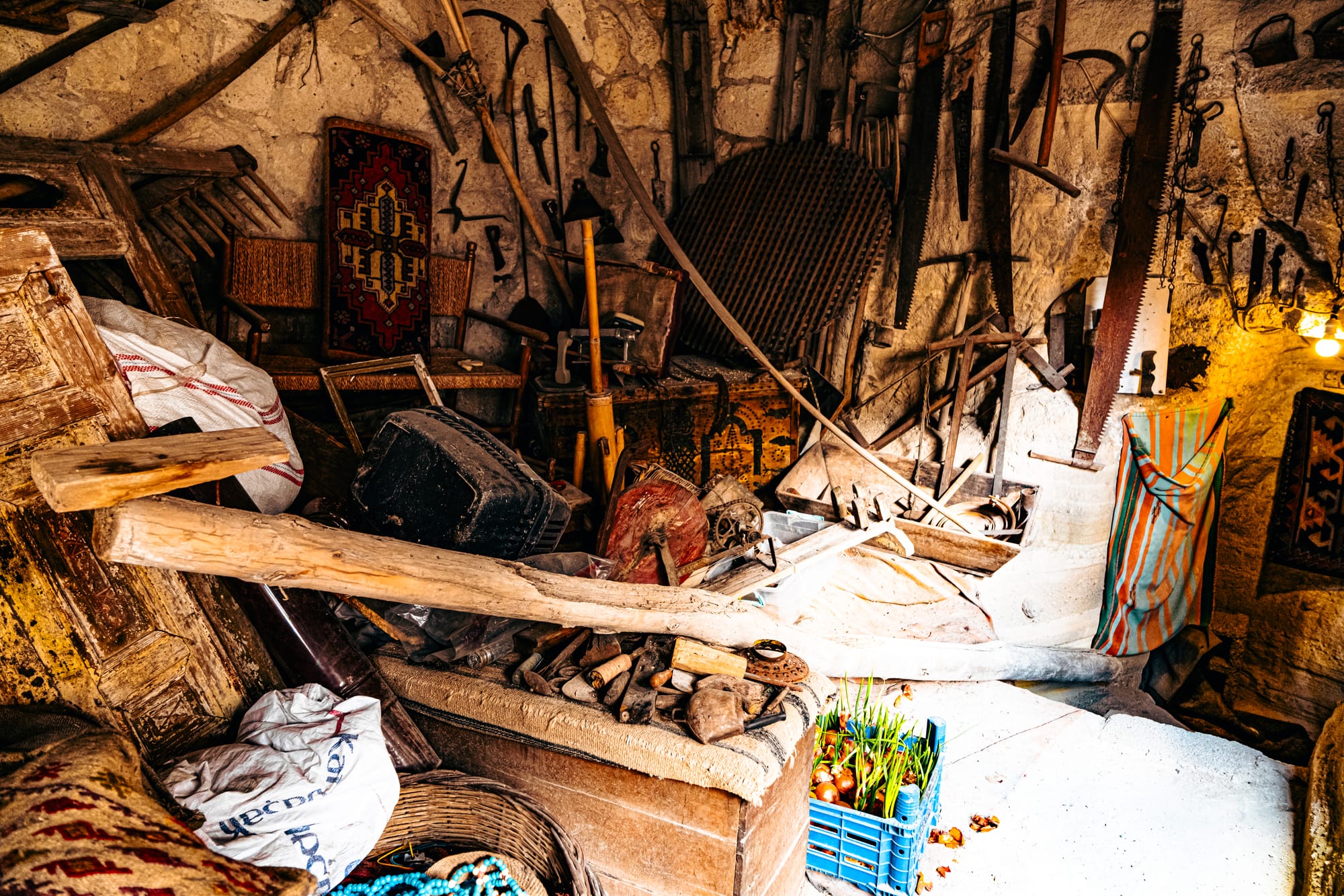 Antique farming tools, wooden furniture, and rustic artifacts in a cave room at Cappadocia Cultural Antique Collection