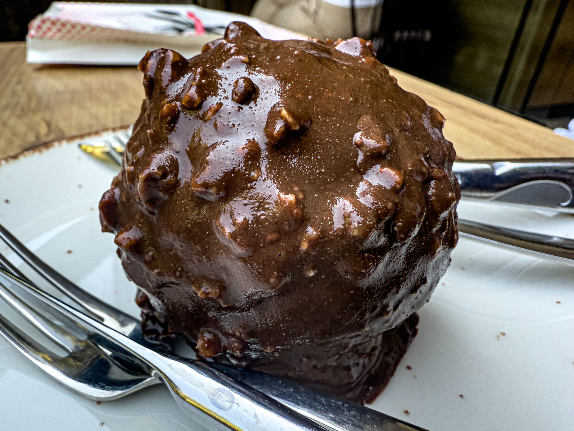 Close-up of a round vegan chocolate dessert ball with a textured chocolate coating and creamy filling, served on a white plate at Vegan House in Antalya