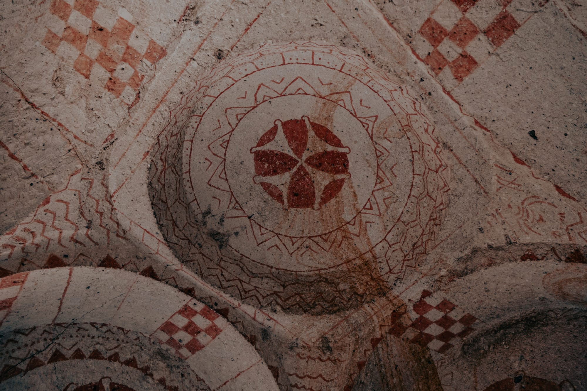 Red geometric fresco design with concentric patterns and checkerboard accents in Göreme Open Air Museum church