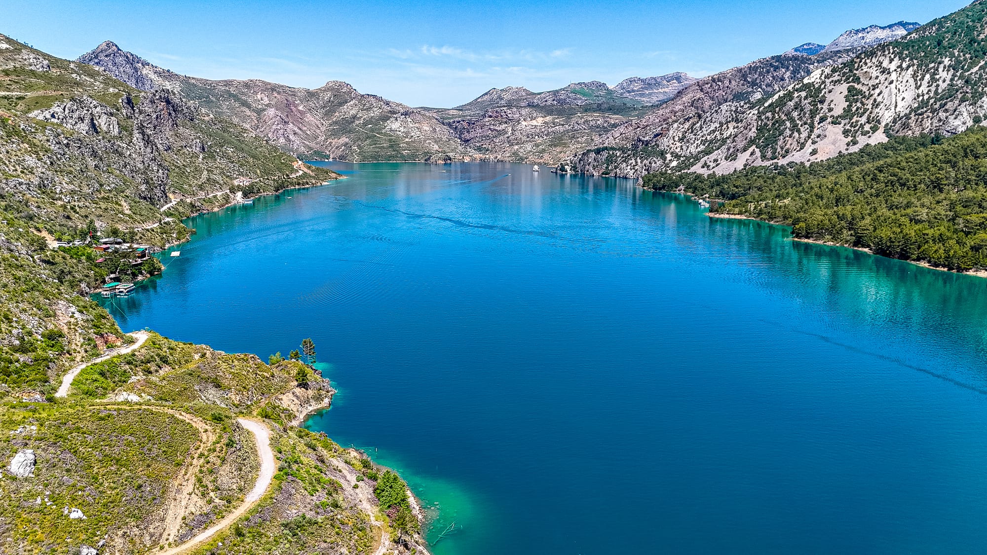 Aerial view of Green Canyon’s reservoir showing calm turquoise water framed by rugged green mountains and forested hillsides